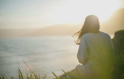 Mental health awareness - calm by the sea A woman standing calmly facing the sea, reflecting mental health awareness and wellbeing