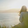 Mental health awareness - calm by the sea A woman standing calmly facing the sea, reflecting mental health awareness and wellbeing
